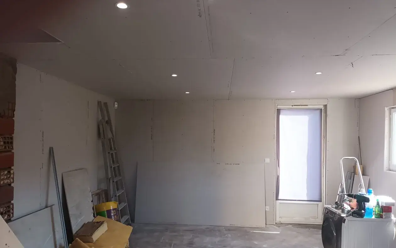 Plafond en plaques de plâtre avec spots encastrés, doublage des murs et mur en brique laissé apparent