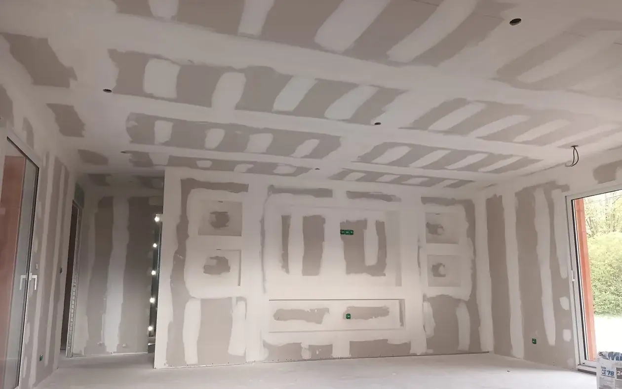 Plafond dont les poutres sont habillées en plaques de plâtre et mur à niches, bandes à joint terminées